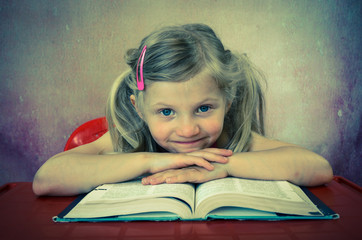 smiling blond little girl with open book