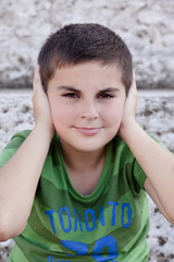 Portrait of a child covering his ears with his hands