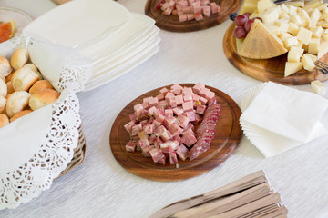 Cubetti di formaggio e salumi su  piatti di legno e tavolo apparecchiato