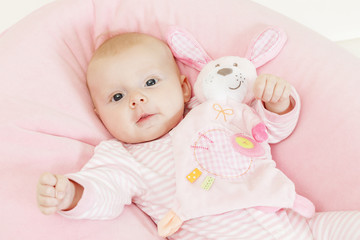 portrait of three months old baby girl with a toy