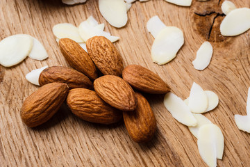 sliced and whole raw almonds on wooden surface