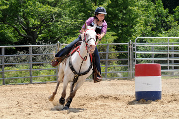 Teenage girl galloping around a turn in a barrel race