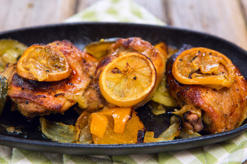 Delicious baked chicken thighs with lemon slices, onion and zucchini
