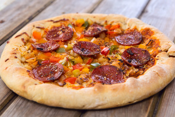 Delicious baked salami pizza served on rustic wooden table