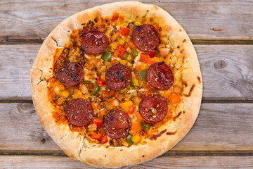 Delicious baked salami pizza served on rustic wooden table