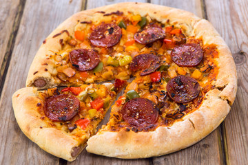 Delicious baked salami pizza served on rustic wooden table