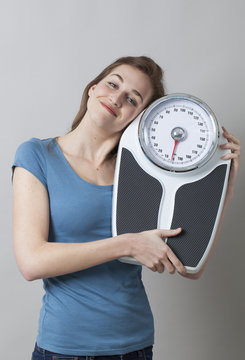 smiling female teenager holding her scale with love and satisfaction