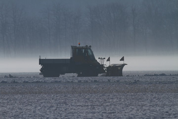Snowplow  removing snow at airfield with low ground fog 