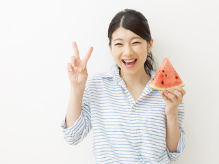 西瓜を食べる女性　ピースサイン