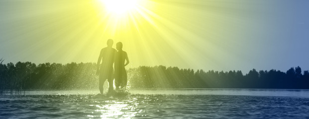 Glückliche junge Menschen laufen und springen am See beim Sonnenuntergang