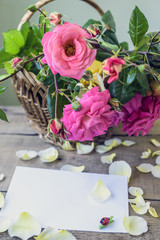 bouquet of pink and yellow roses in a wicker basket and white sheet of paper for a message