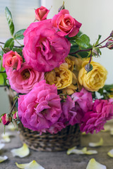 bouquet of pink and yellow roses in a wicker basket