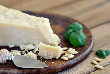 Parmesan - Parmesanmesser, Pinienkerne, Basilikum auf Holzbrett