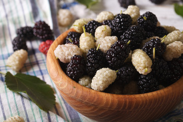 Ripe white and black mulberries in a wooden bowl macro
