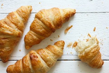 Golden croissants on rustic white wood, from above. - Powered by Adobe