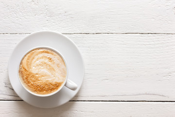 Cappuccino in cup on rustic painted wood. From above.