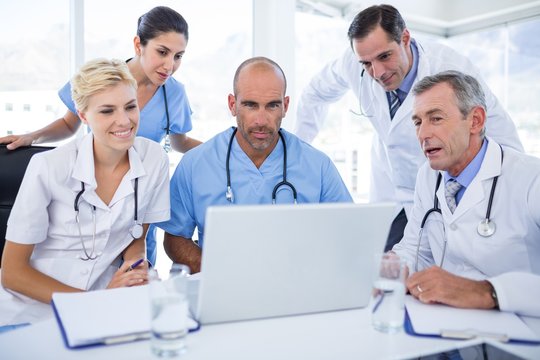 Teams of doctors working on laptop computer 