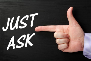 Finger pointing at the phrase Just Ask on a blackboard