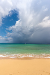 Beach on tropical island. Clear blue water, sand, clouds. 