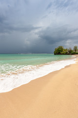 Beach on tropical island. Clear blue water, sand, clouds. 