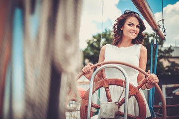 Stylish wealthy woman on a luxury wooden regatta