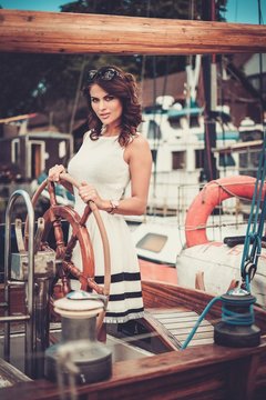Stylish wealthy woman on a luxury wooden regatta