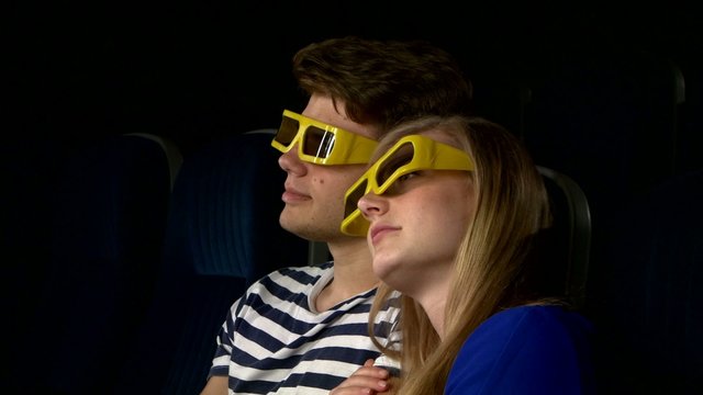 Couple in cinema watching a movie with 3D glasses. Close Up