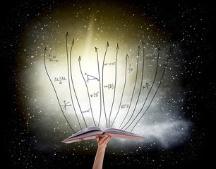 Human hand holding book with flying math formulas