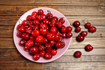 Plate with cherries on wooden table