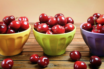 Bowl with cherries on wooden table