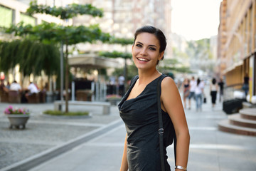 Young attractive cheerful woman walking in city.