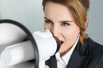 Young business woman shouting with a megaphone