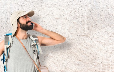 Backpacker talking to mobile over white background
