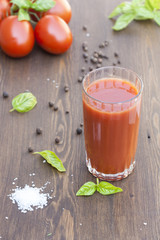 Tomato juice, tomatos, herbs and spices on wooden table