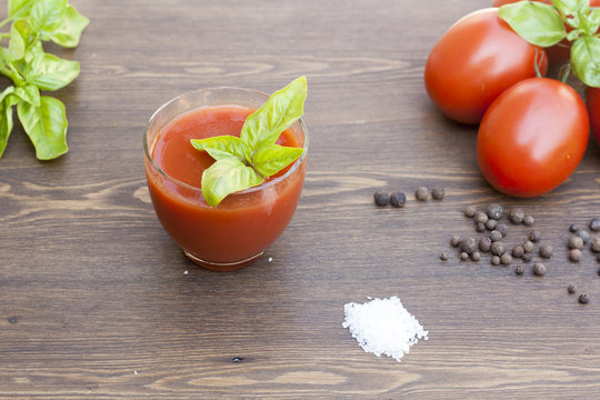 Tomato juice, tomatos, herbs and spices on wooden table