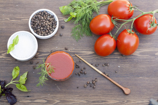 Tomato juice, tomatos, herbs and spices on wooden table