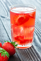 Glass of strawberry drink on wooden table.