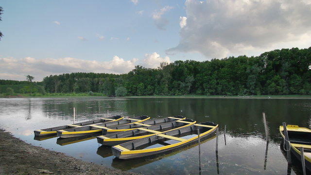 Several wooden row boats for fishing and rental, painted bright yellow, waiting for tourists on a freshwater lake