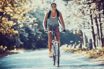 Gracefully biking through the forest, a skilled female athlete enjoys the mountain bike ride.