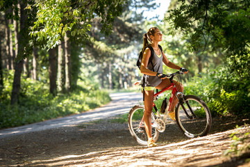 Fototapeta na wymiar Pausing her mountain bike ride, female takes a break, admiring the natural beauty surrounding her in the forest.