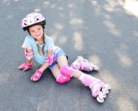 Cute smiling little girl in pink roller skates