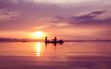 Naklejka na ściany i meble Man and woman in a boat at sunset