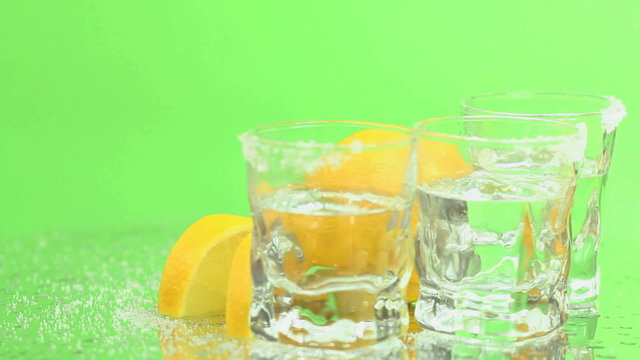 Green Screen Tequila shots - Tequila shots in frosty glasses with salt and lemon rotating on a green screen background, seamless loop.
