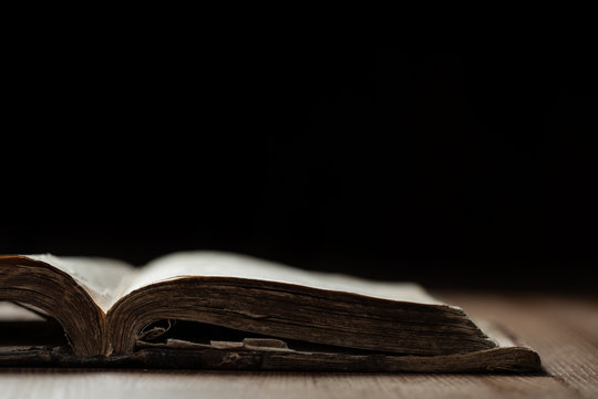 Image of an old Holy Bible on wooden background in a dark space with shallow depth of field