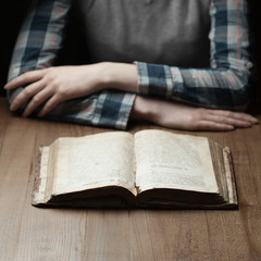 Naklejka premium woman reading the bible in the darkness over wooden table