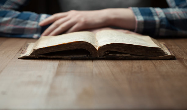woman reading the bible in the darkness over wooden table. Bible is opened on a table