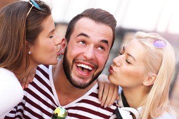 Two women kissing a man