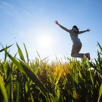  woman jumping on grass meadow. Beautiful day outside.