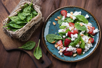 Salad with strawberries, spinach leaves and cheese, top view