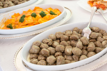 Bocconcini di carne in primo piano e ravioli gialli, sullo sfondo